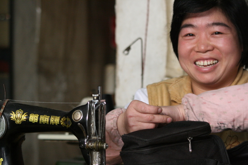 Meihua Town - A kind taylor fixing my camera bag. She invited me to lunch at her stall.  