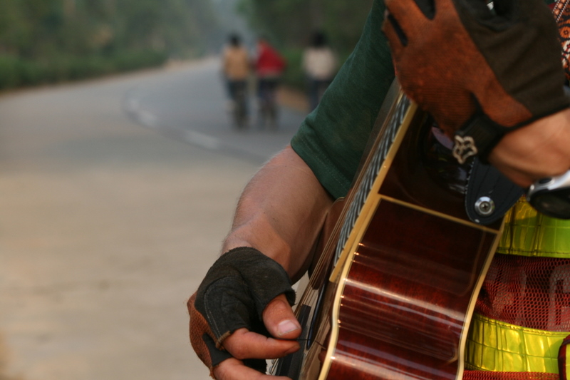 Guangdong - Drew playing guitar on the side of road while Jim fixes his flat tire