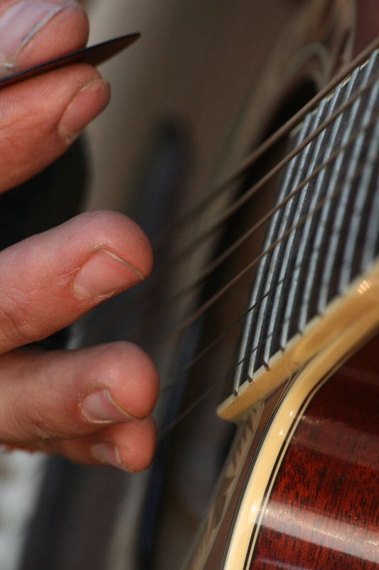 Guangdong - Drew playing guitar on the side of road while Jim fixes his flat tire