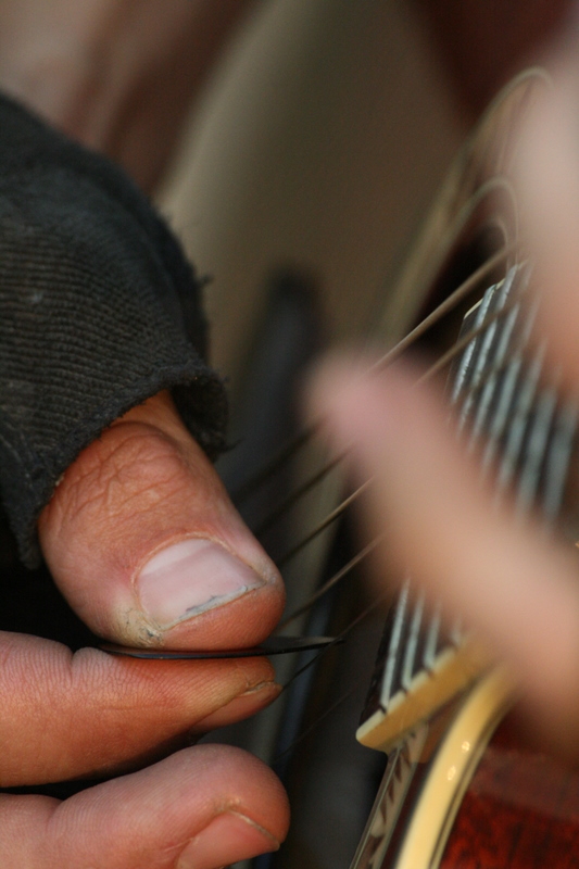 Guangdong - Drew playing guitar on the side of road while Jim fixes his flat tire