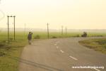 India, West Bengal - Drew and Jim take a curve on a beautiful Indian county road through rice fileds of central West Bengal.