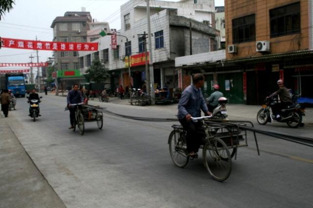 China - Guangdong Prov. - using teamwork tricycles to move heavy rebar.