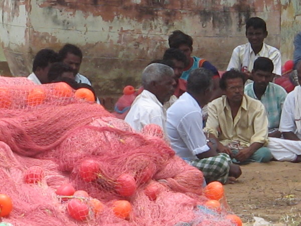 Men sit next to their nets, organizing.