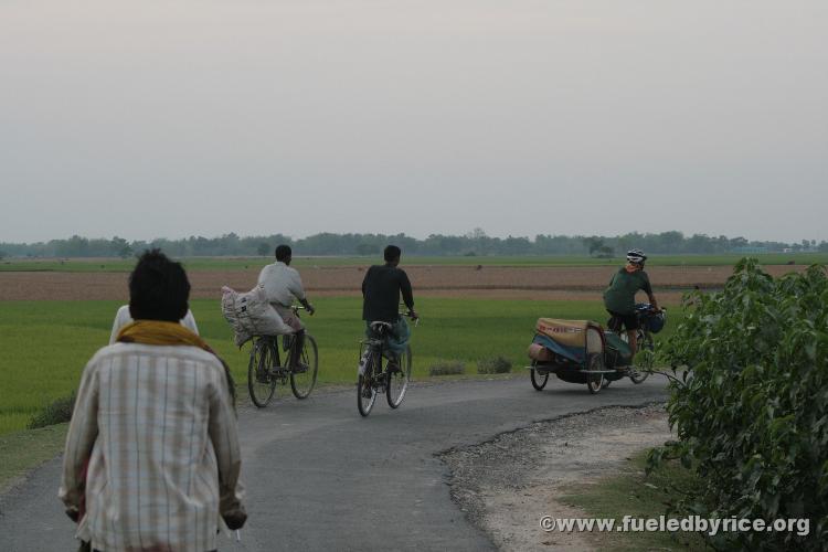 India, West Bengal - A few locals trail Drew and the Bandwagon on a beautiful back county road