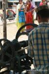 Nepal, west lowlands - pressing sugar cane at another sugarcane stand, while a couple colorful ladies enjoy their beverage; came