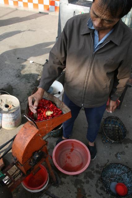 Oct 9 2007 - Changrong village, Jiangsu Prov, China. Morning on the street, making pepper paste - grind up peppers with a little