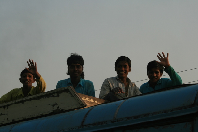 India, West Bengal - Indians often ride on the tops of overcrowded buses as these young men are.  Fresh air and space often make