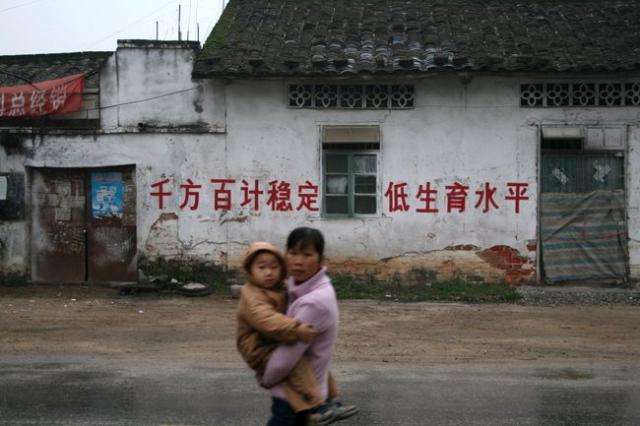 China, Guangxi prov. - Woman with child with population reduction propaganda sign in the background. (Peter)