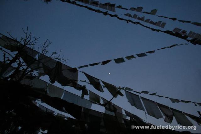India, Darjeeling town - a crescent moon through Tibetan Buddhist prayer flags