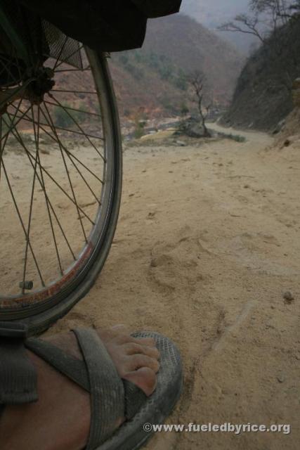 Nepal, Himalayan foothills, Sindhuli area backroad to Kathmandu - Peter's foot and wheel on the worst kind of rough road: sharp